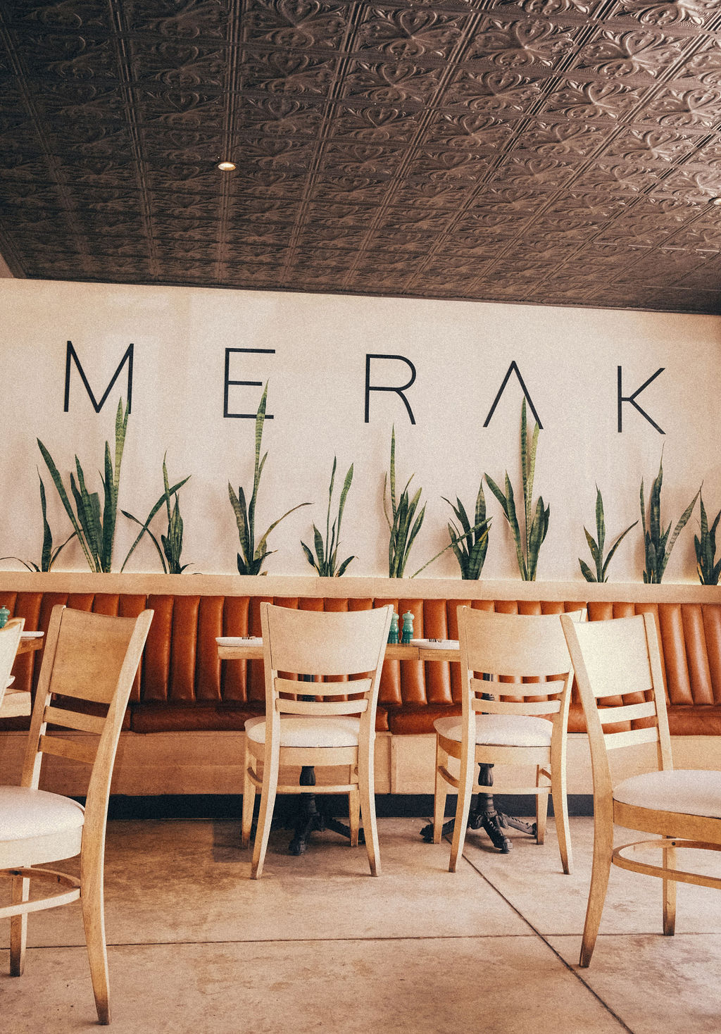 Merak on Main interior with signage, banquette seating and plants
